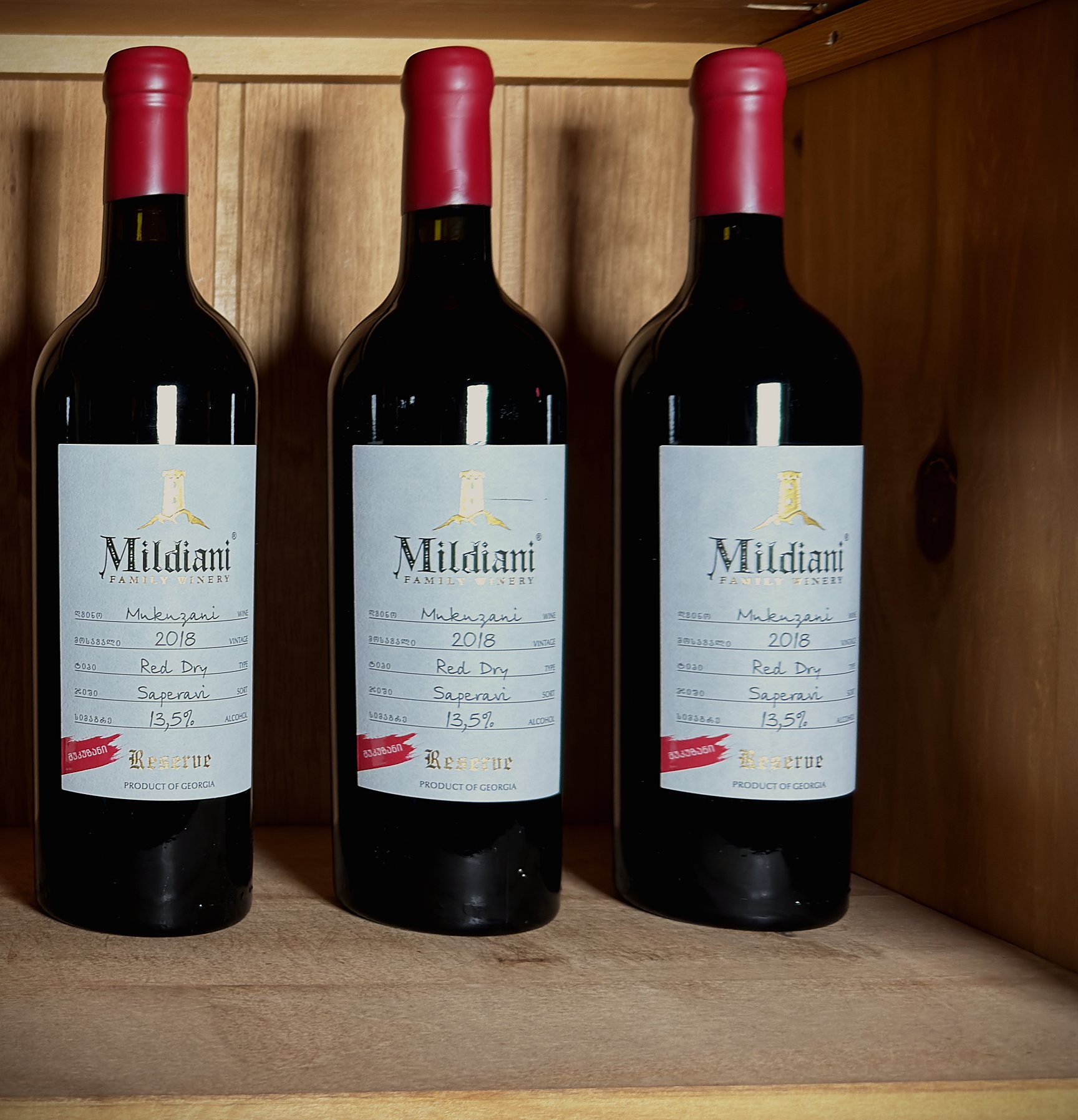 Drei Flaschen Mildiani Mukuzani Reserve im Regal des Weinhauses