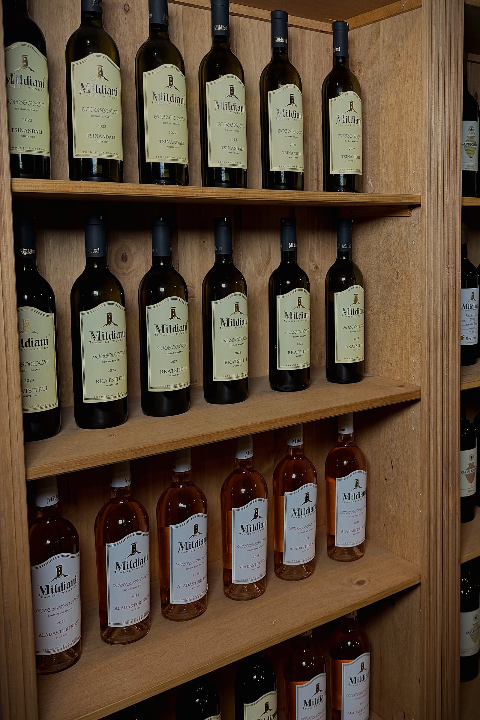 Regale mit Weiß- und Roséweinen von Mildiani an der Wand des Weinhauses